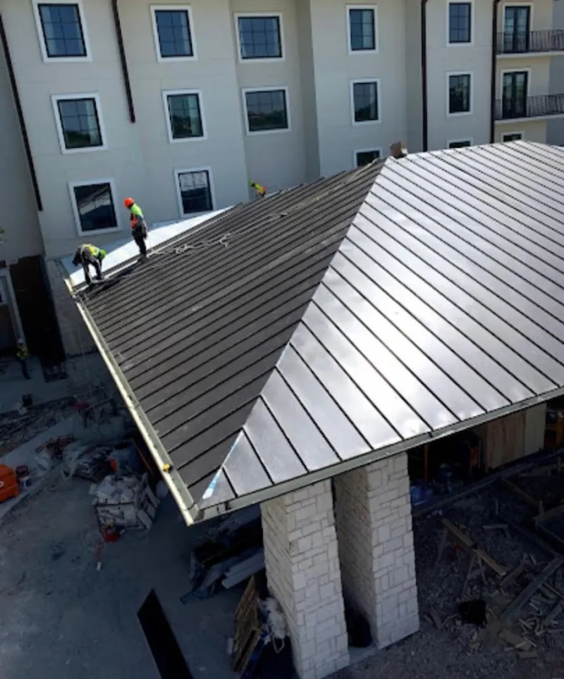 Crew installing standing seam metal roof panels on a commercial project in Galloway